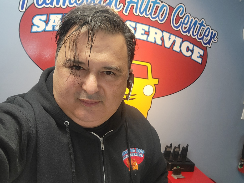 a man taking a selfie behind the behind the auto center logo